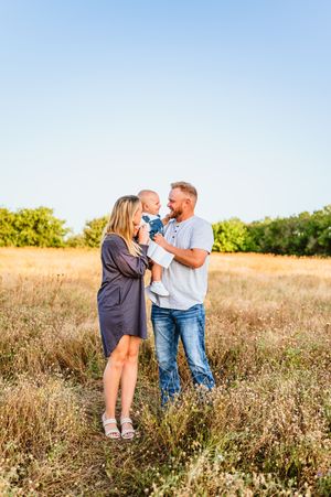 A happy family with a baby enjoys a sunny day together in a golden open field.