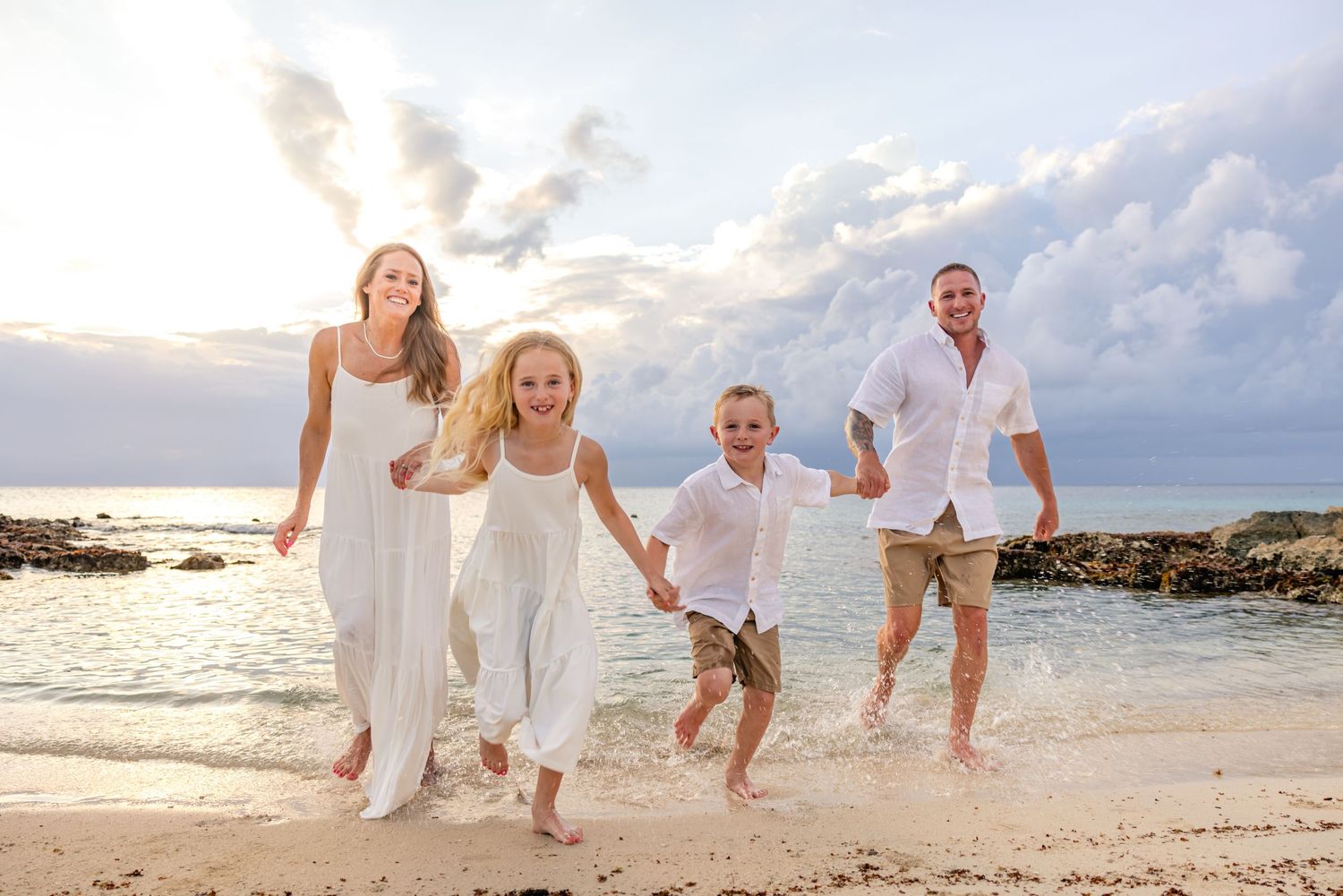 Happy family of four running on a sandy beach at sunset at Presidente InterContinental Cozumel for a photography session