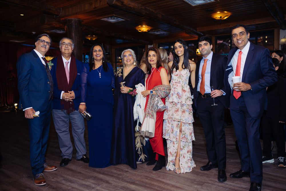 Group of elegantly dressed people posing together at a formal evening event in a warmly lit venue.