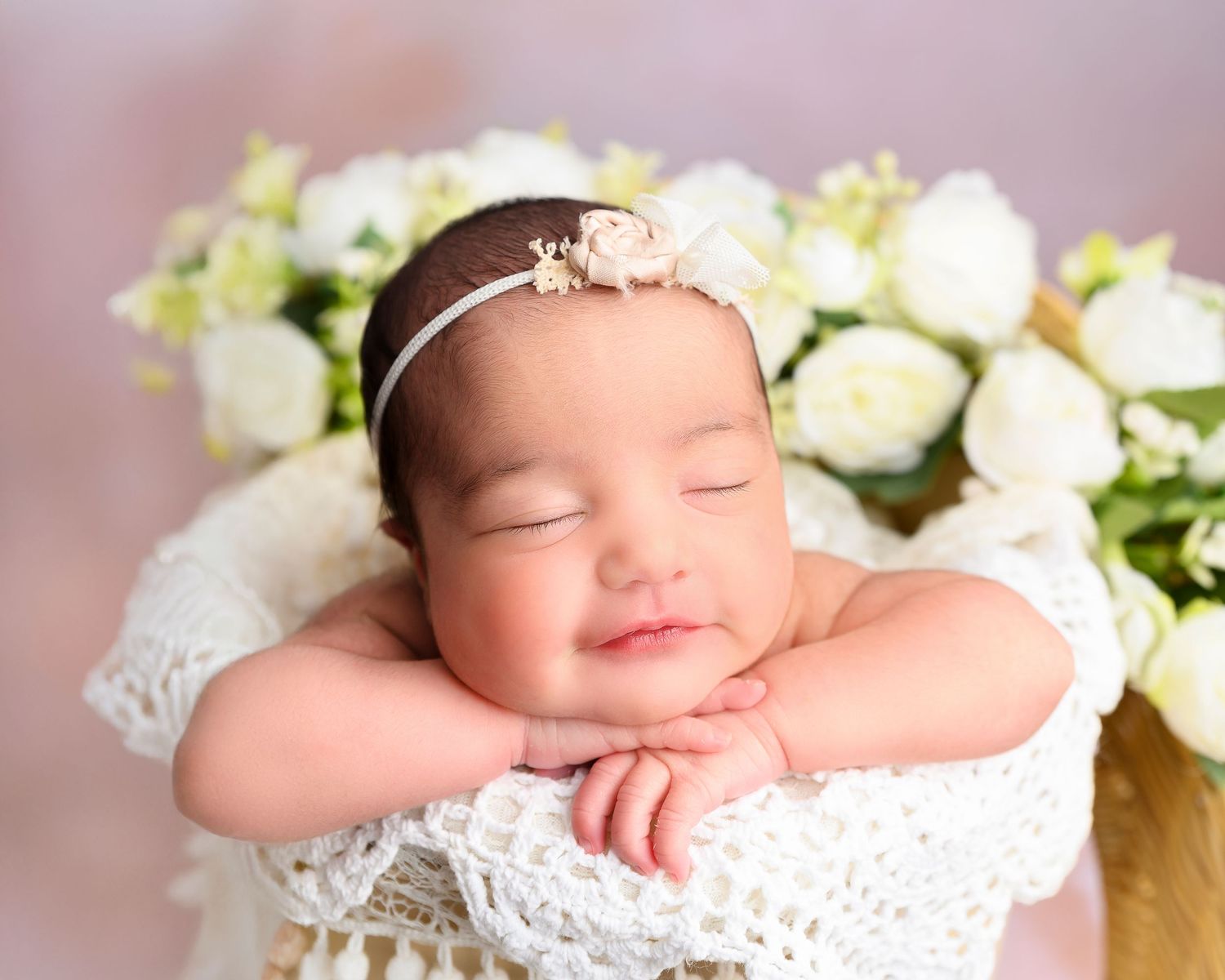 Sleeping newborn baby posed with soft white flowers by a Tampa newborn photographer