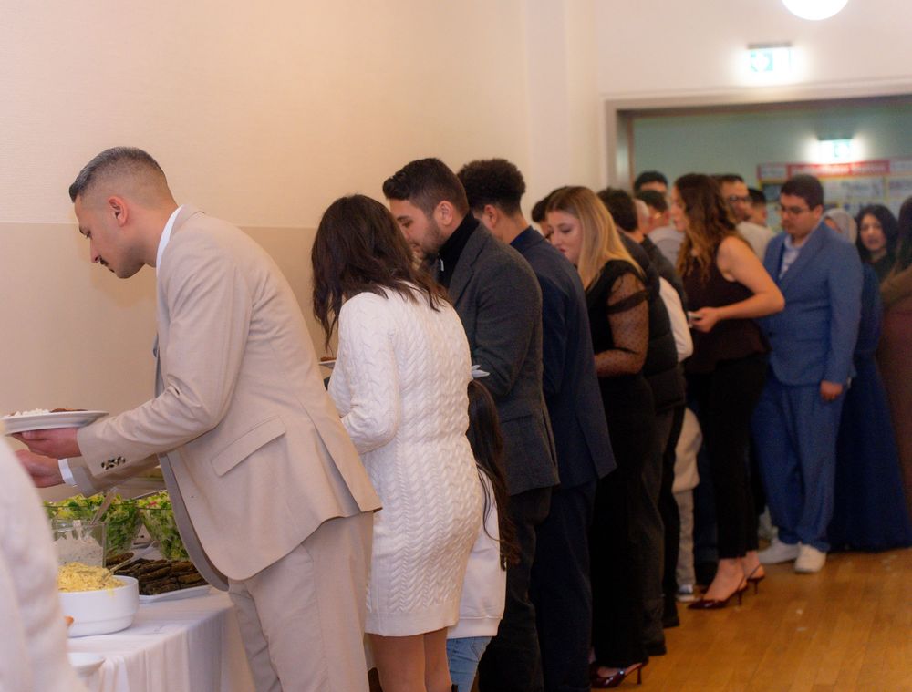 Guests in formal attire line up at a buffet table during an elegant catered event or party.