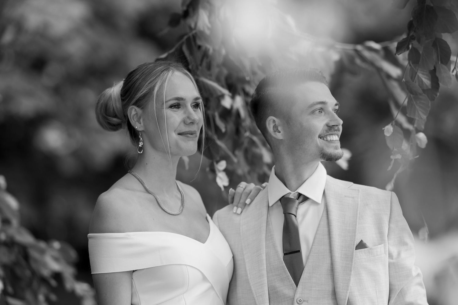 Black and white photo of an elegant couple sharing a romantic moment, touching foreheads in a tender embrace.
