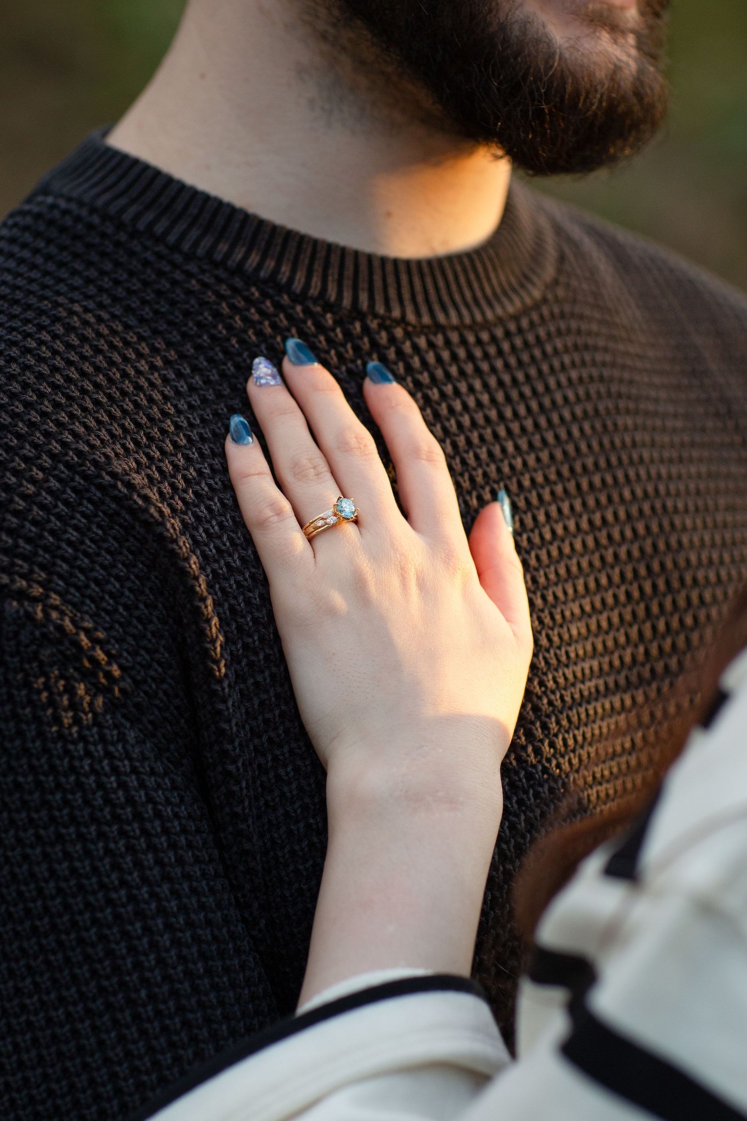 Engagement ring on display in the golden hour light on partners chest during surprise proposal photo session in Perth