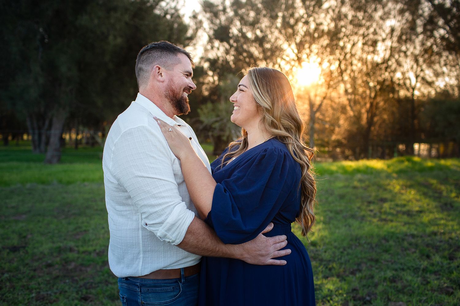 Couples looking into each others eyes in a paddock at golden hour during engagement session in Perth