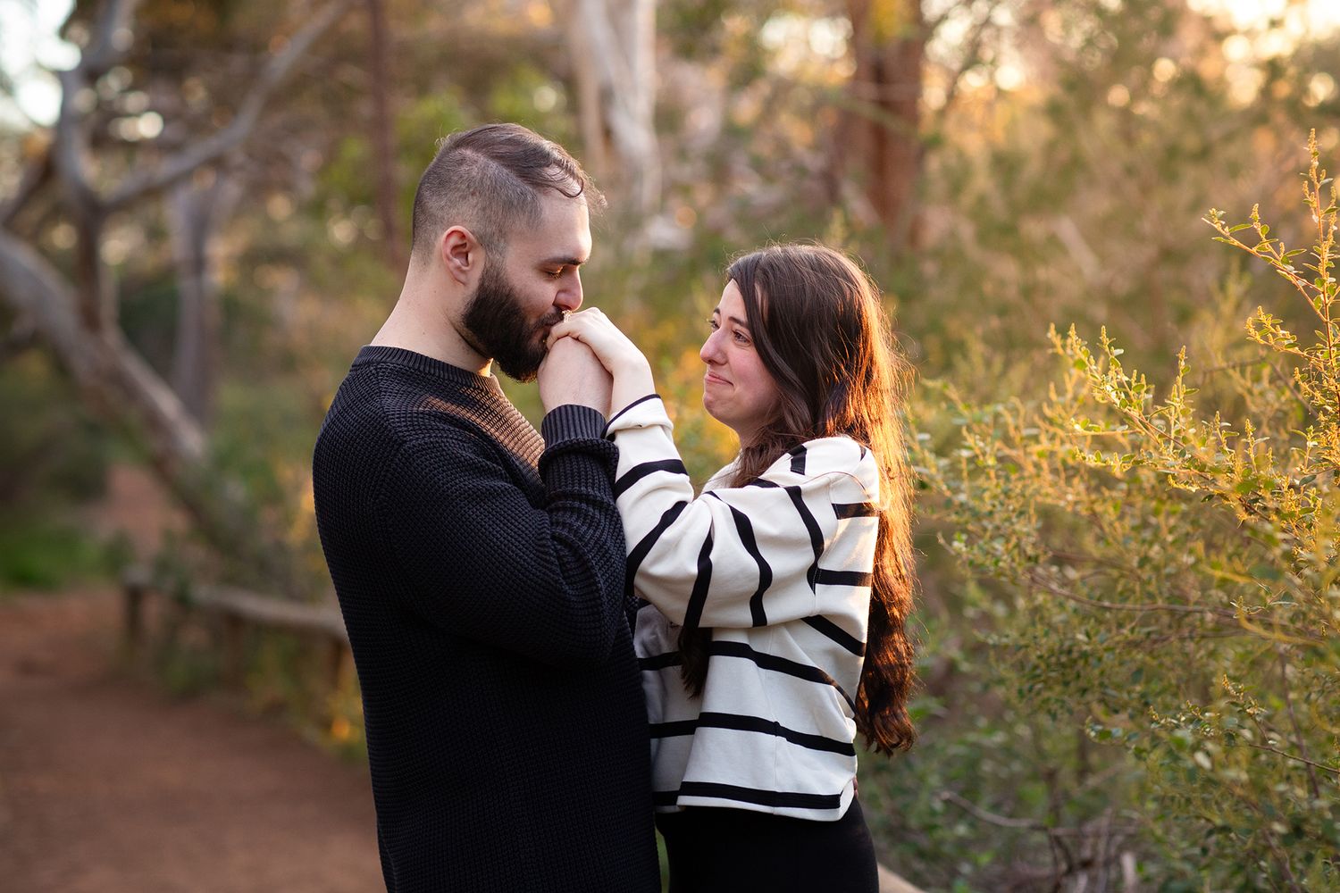 Newly engaged couple sharing an emotional kiss of the hand in Perth engagement photo session during golden hour
