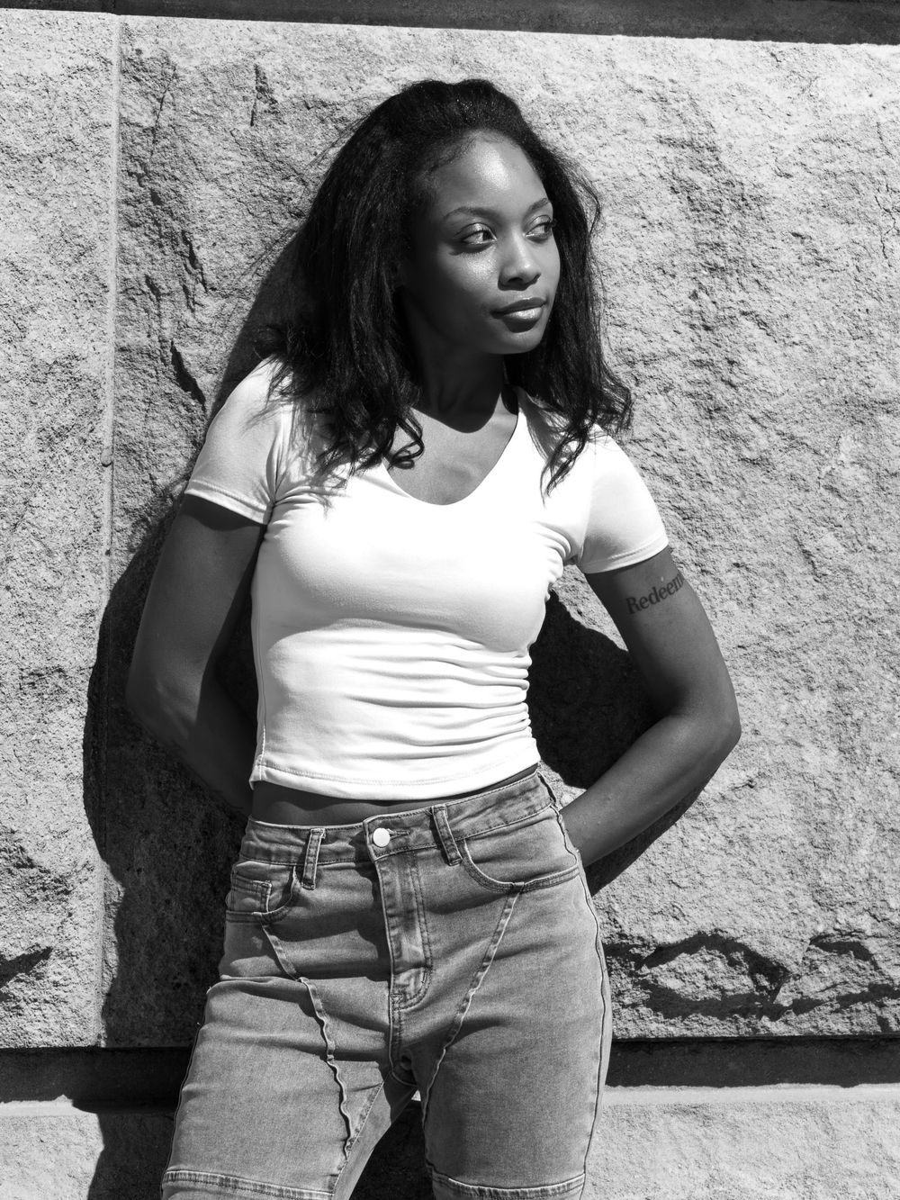 Black and white lifestyle portrait of Genesis Dudley wearing a white T-shirt and jeans outdoors.