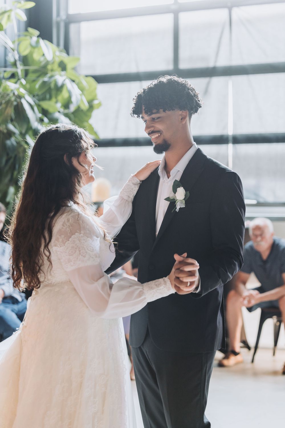 Bride and groom share their first dance at wedding reception, smiling joyfully in elegant attire.
