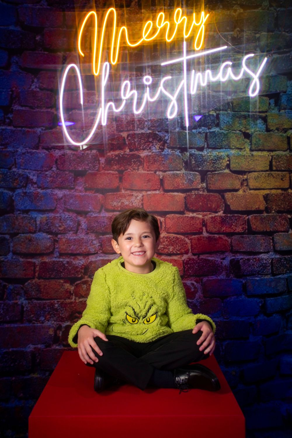 A series of four photos showing someone in a bright yellow sweater posing against a brick wall with neon lighting.