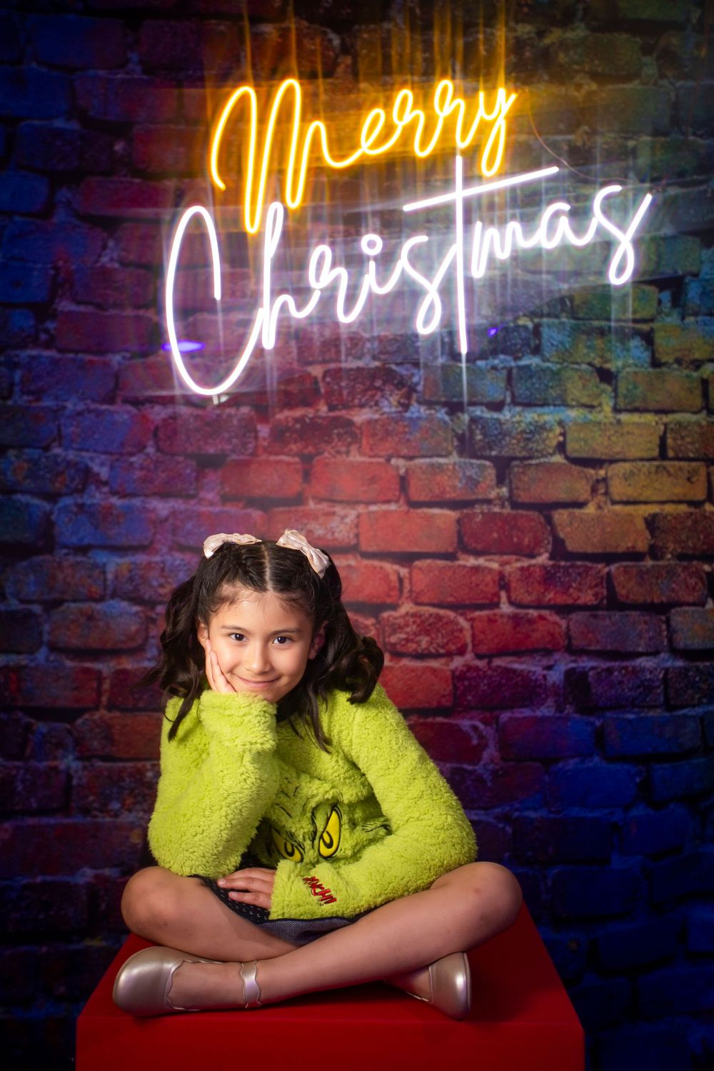 A series of photos against a brick wall with neon lighting shows a person in a bright yellow sweater striking different poses.