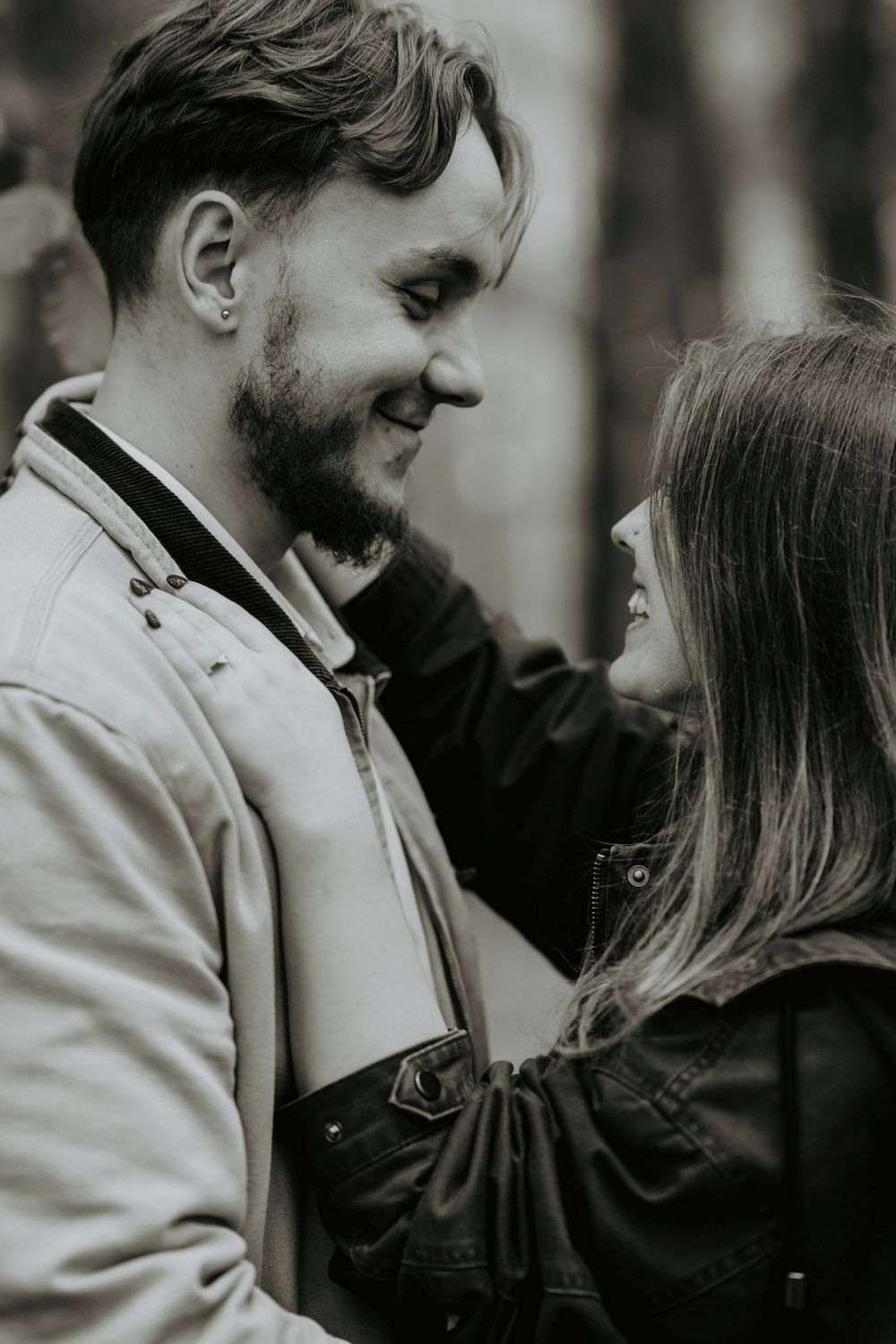 Black and white photo of a smiling couple gazing at each other affectionately outdoors.