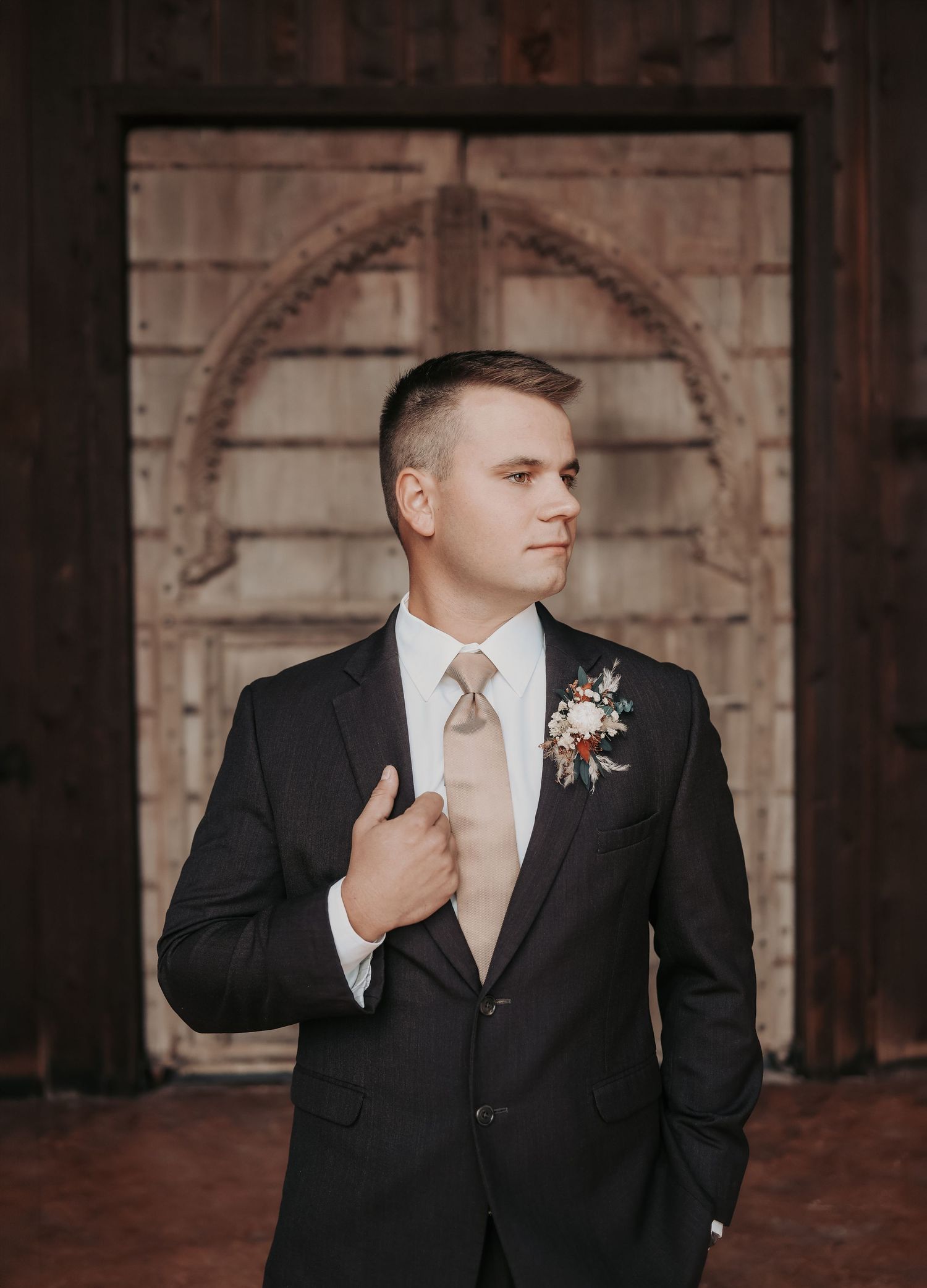 Groom adjusting wedding suit while getting ready at Lucky Spur Ranch