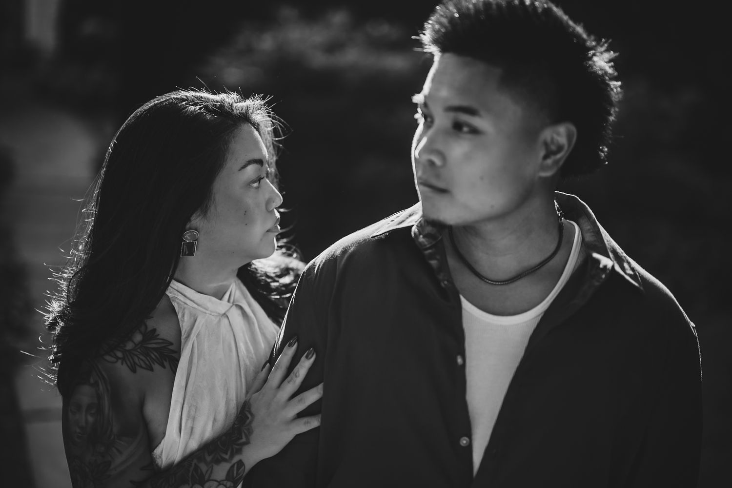 A black and white photo of a young Asian couple sharing an intimate moment outdoors at night.