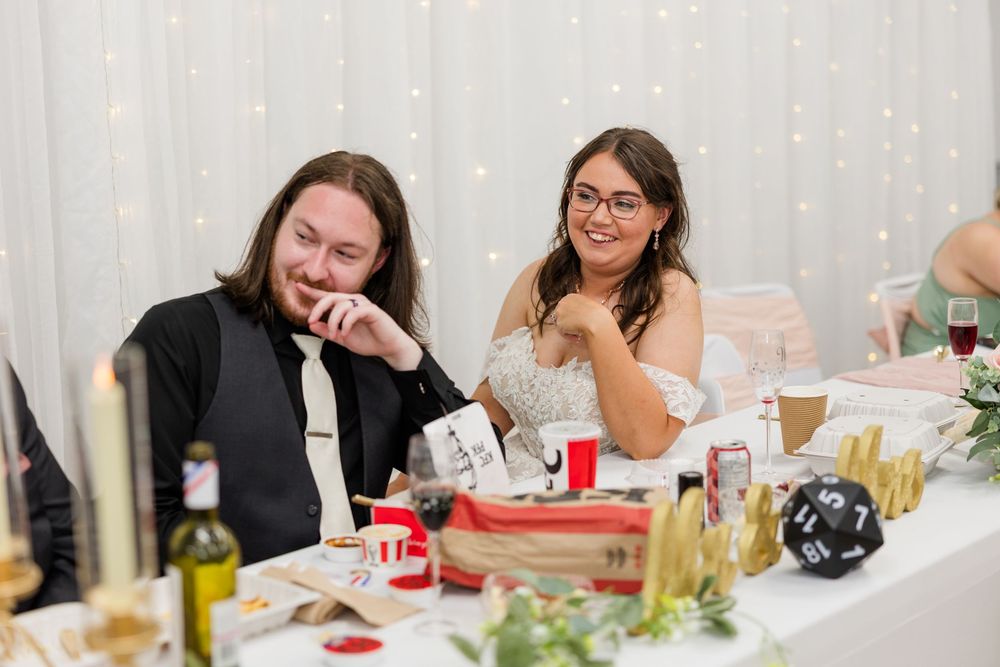 Bride and groom laughing at wedding reception table decorated with dice and festive items.