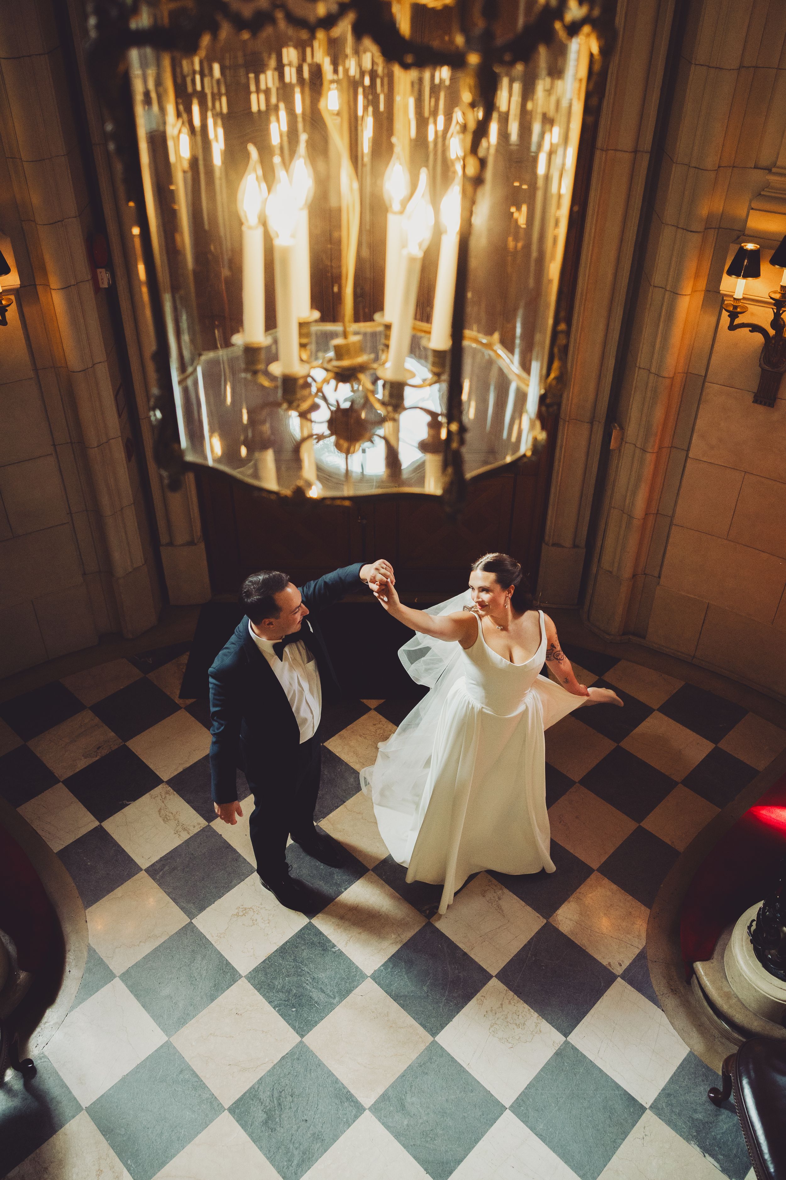 Bride and groom dancing under a grand chandelier on a checkered floor in an elegant wedding venue at the meridian house washington dc