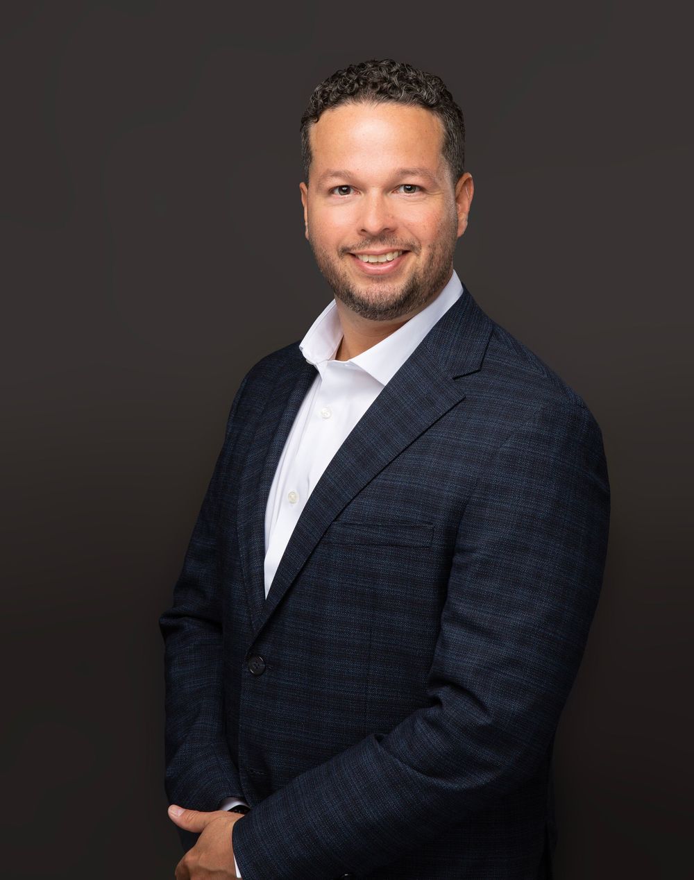 Smiling man in a dark suit and white shirt on a black backdrop, male business headshot in Sarasota