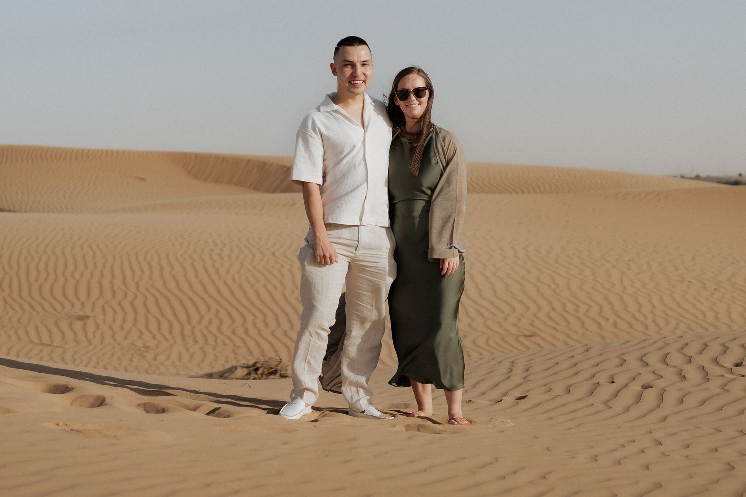 Couple standing together in the Dubai desert before a surprise proposal