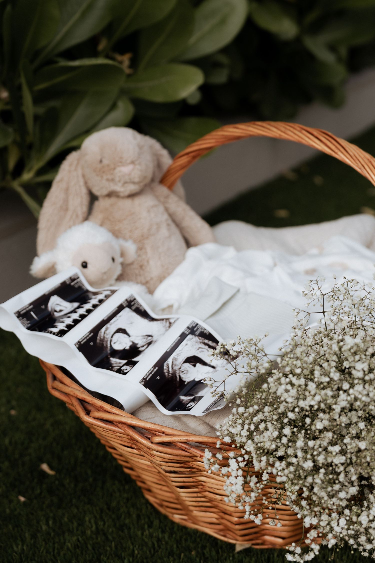 Wicker basket with ultrasound photos, soft toys and gypsophila flowers for a maternity session in Dubai