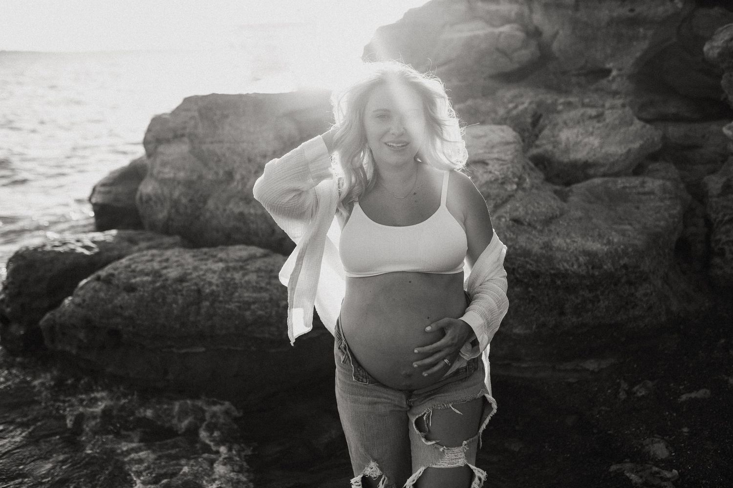 Natural maternity photos of expecting parents along the rocky shore at Lake Grapevine