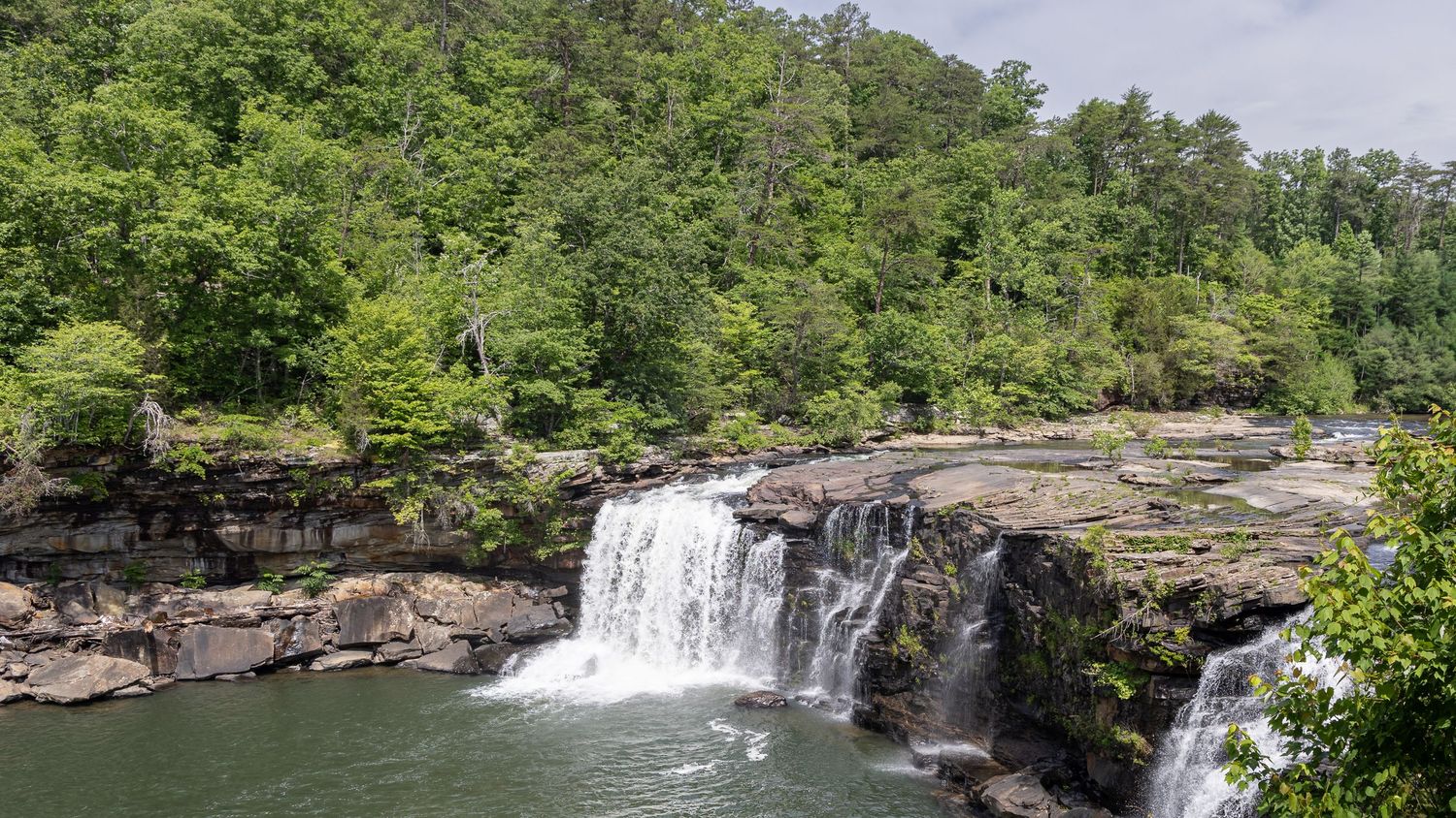 Waterfall at G.E. Hill Bridge in Little River Canyon, Alabama, surrounded by forest and rocky cliffs.