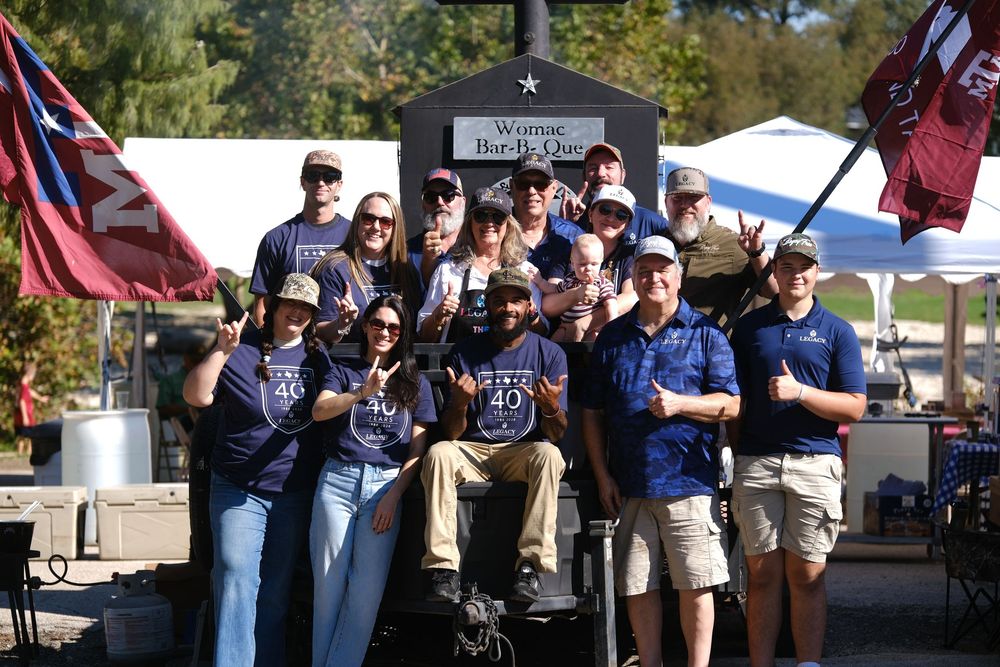 Group of people in matching blue shirts posing outdoors at a festive event near a star-decorated backdrop.