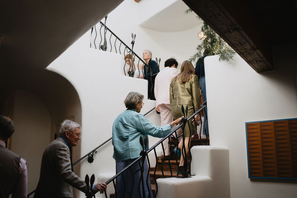 Elegantly dressed guests socializing on a winding staircase inside a sophisticated venue during a formal event.