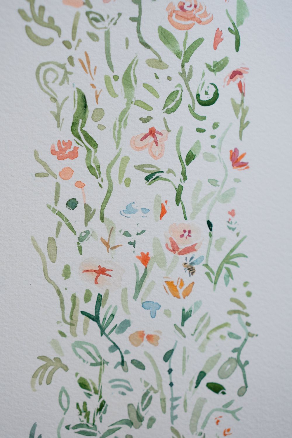 Delicate watercolor painting of wildflowers and green leaves in soft pastel pink, coral, and sage tones on white paper.
