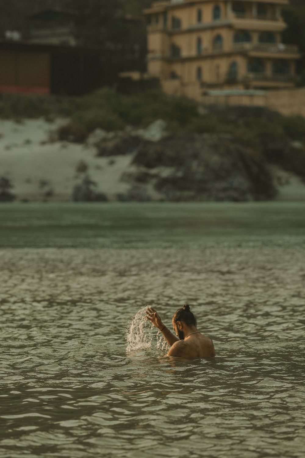 Man bathing and splashing in the sacred Ganges River in Rishikesh, India.