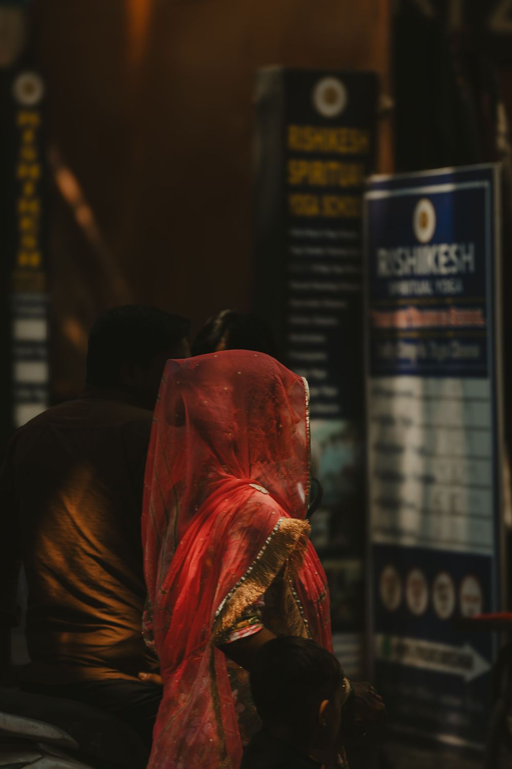 Woman in red dupatta praying at Rishikesh Spiritual Yoga School at night.