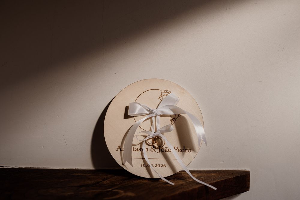 Elegant round wooden wedding keepsake box with white ribbon bow on rustic shelf.