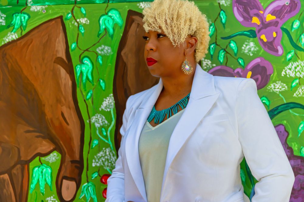 Stylish outfit photographed against a colorful mural background with green and purple designs.