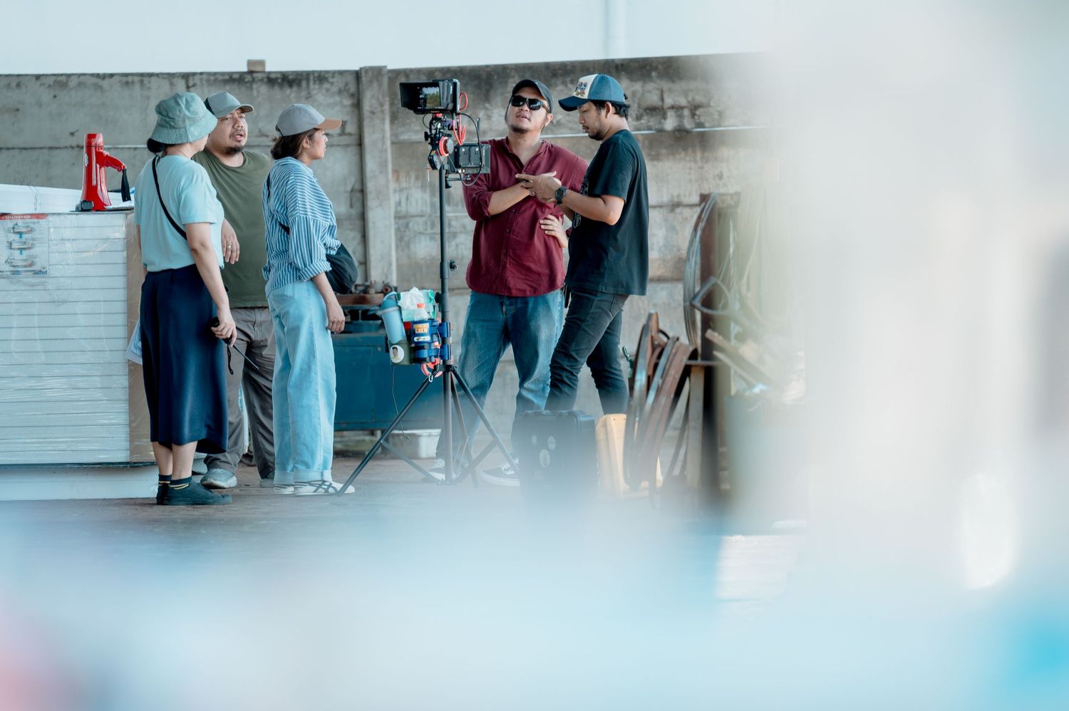 Film crew members collaborating on an outdoor video production set with camera equipment.