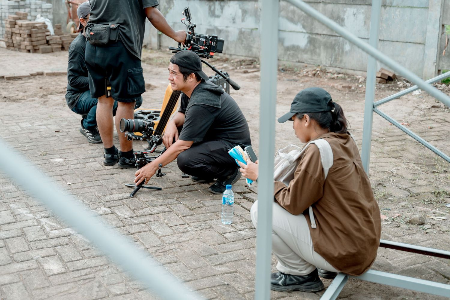Film crew crouching on pavement reviewing camera footage on a film set outdoors.