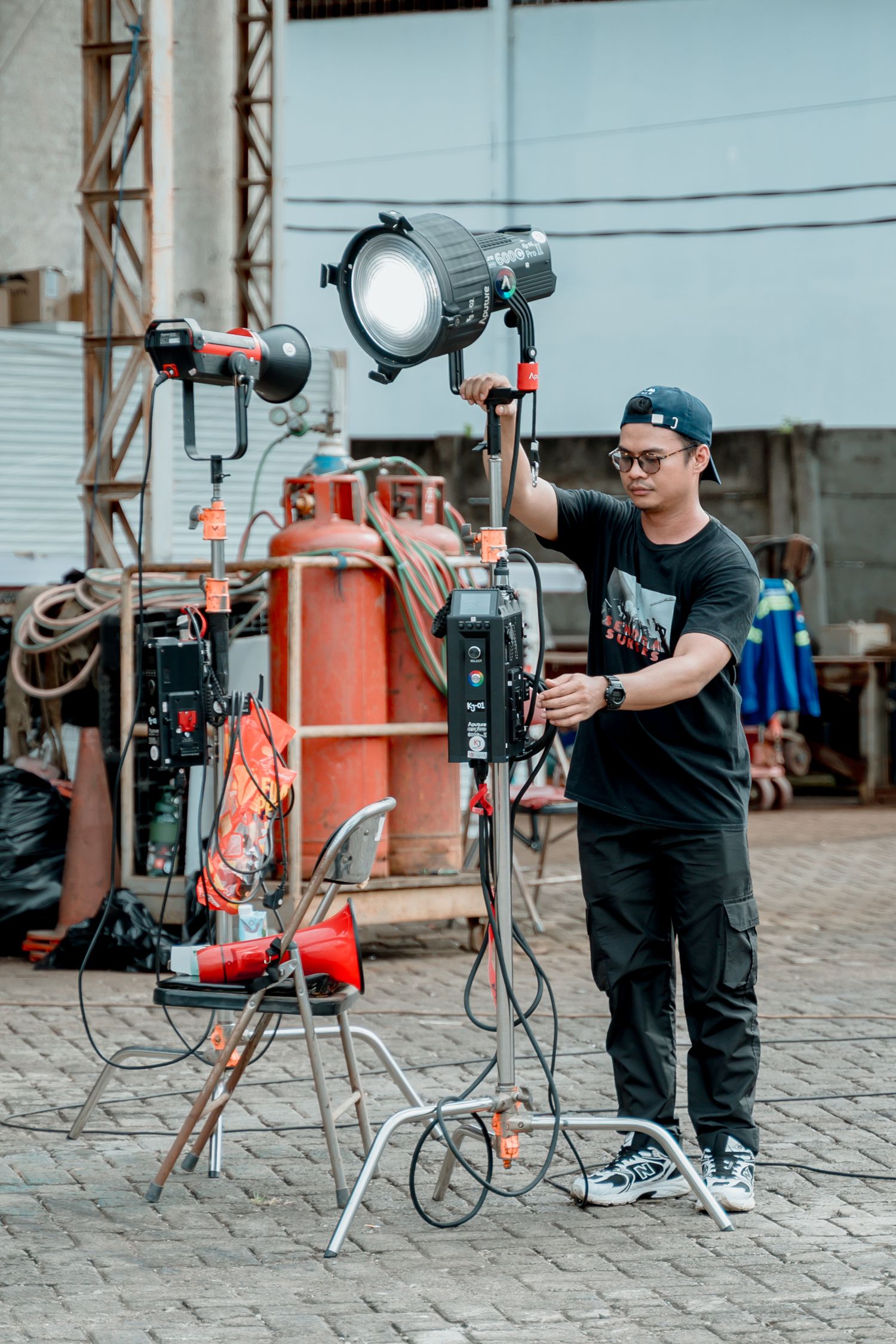 Cinematographer adjusting professional LED studio light on a film production set outdoors.