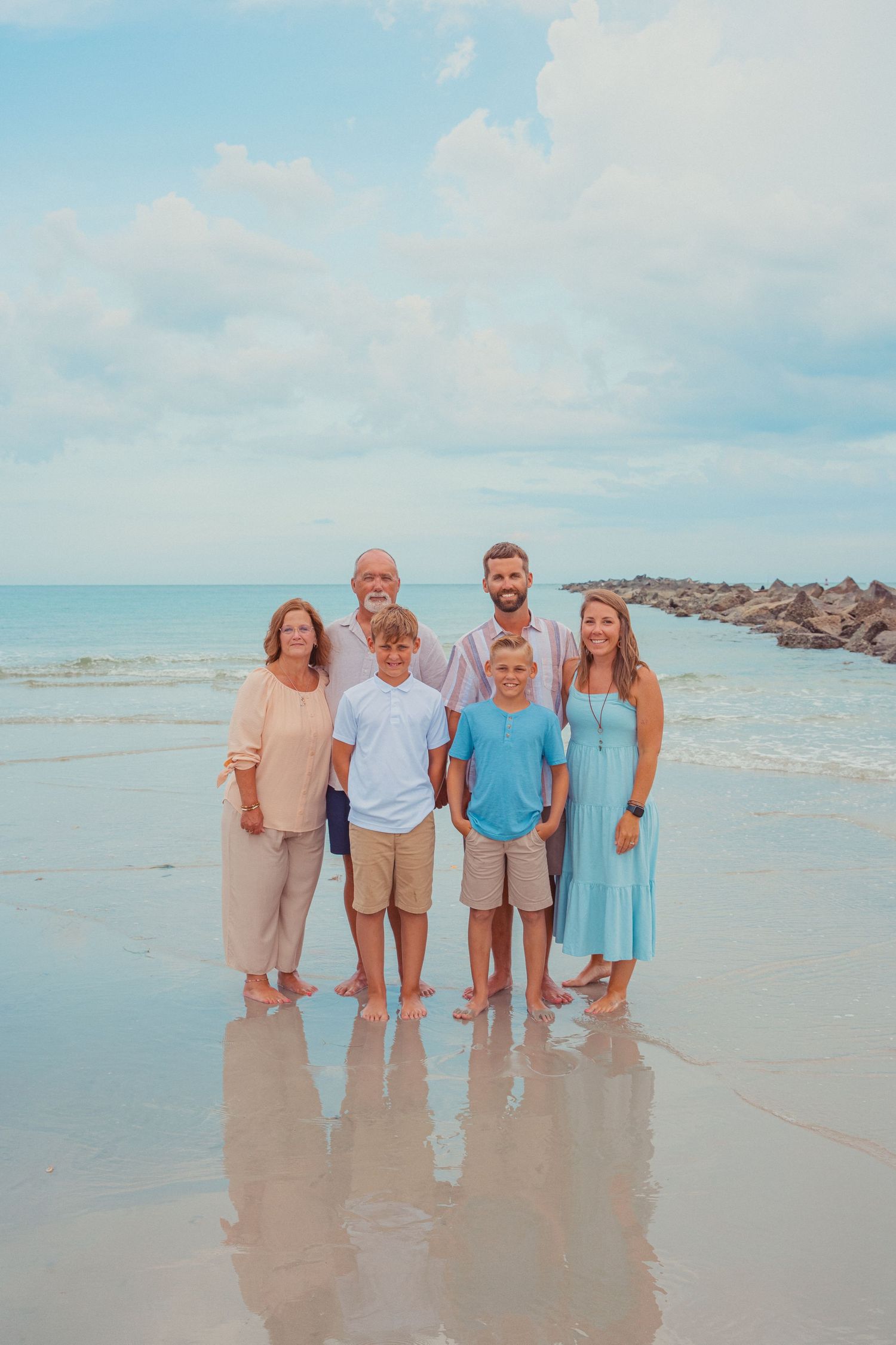 A family of 6 poses for a picture on the beach during summer in Fort Pierce, Florida