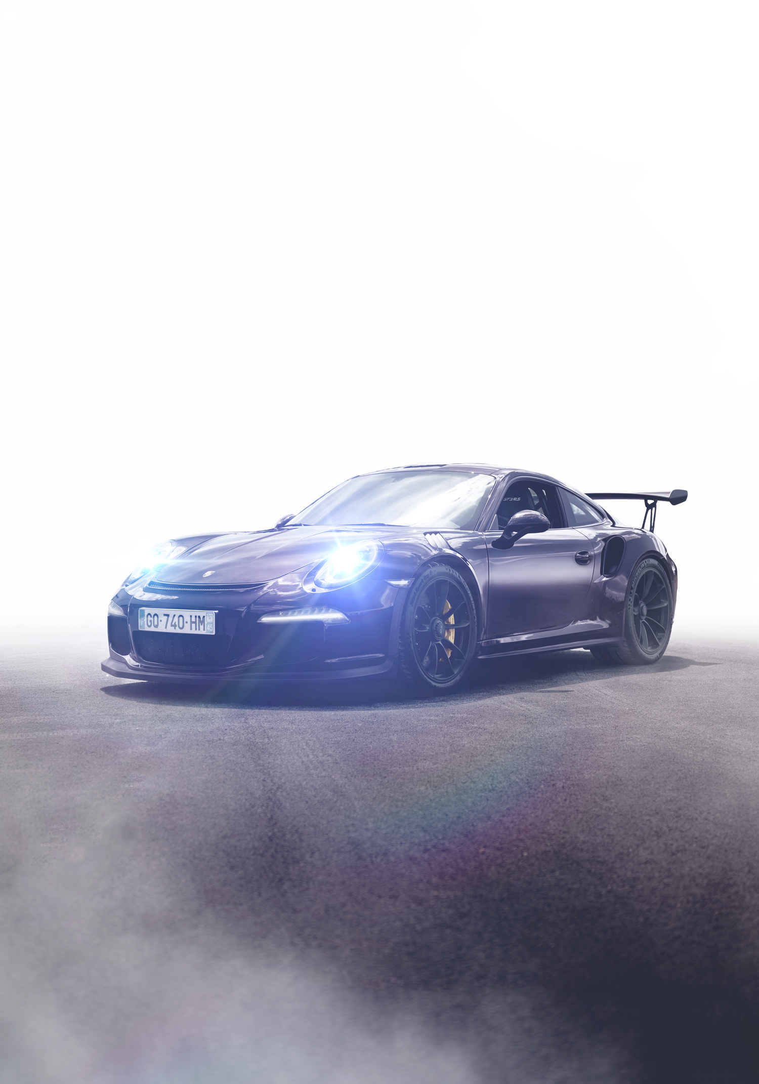 Dark Porsche 911 GT3 RS with rear spoiler and blue headlights surrounded by dramatic smoke on a bright white background.