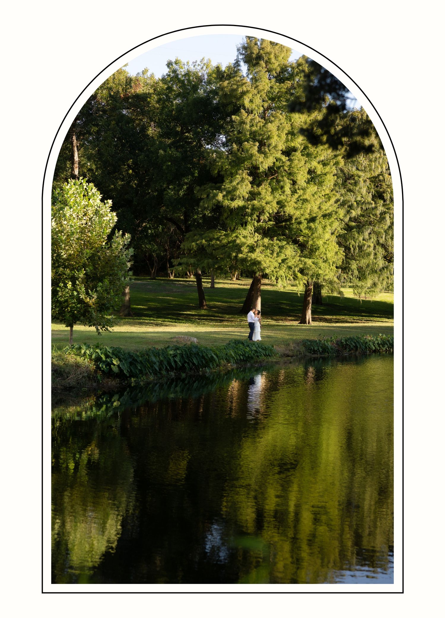 Arched wide photo of a couple dancing by the side of a river at sunset