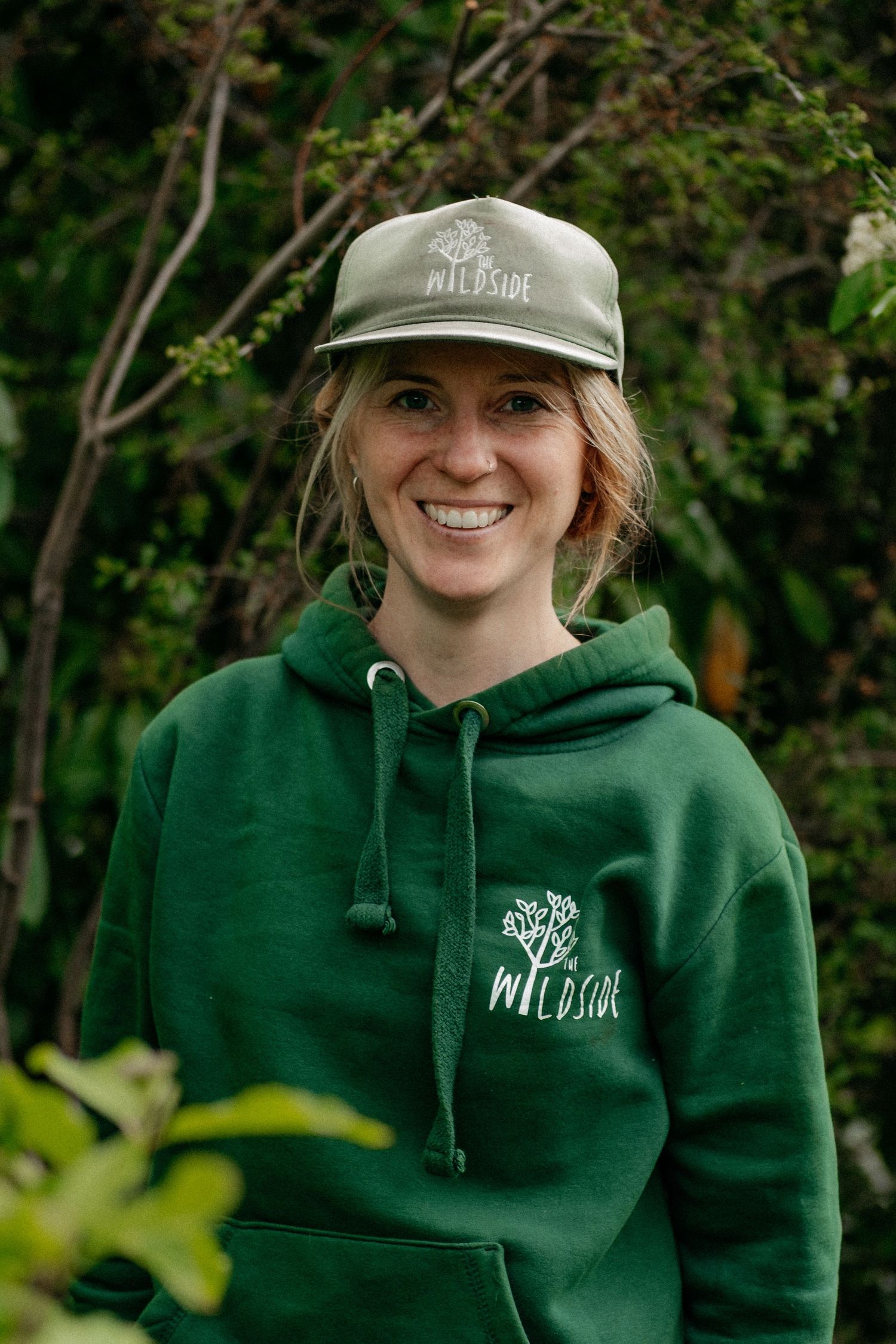 Brand photography in Newcastle, North Tyneside and Whitley Bay, featuring a smiling woman outdoors in a green hoodie and cap.
