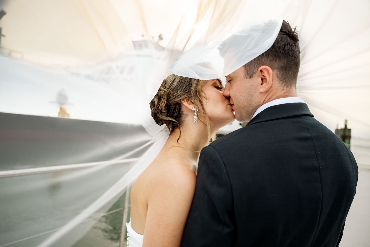 A romantic proposal scene set between rows of grapevines in a scenic vineyard with white flowers and a blanket.