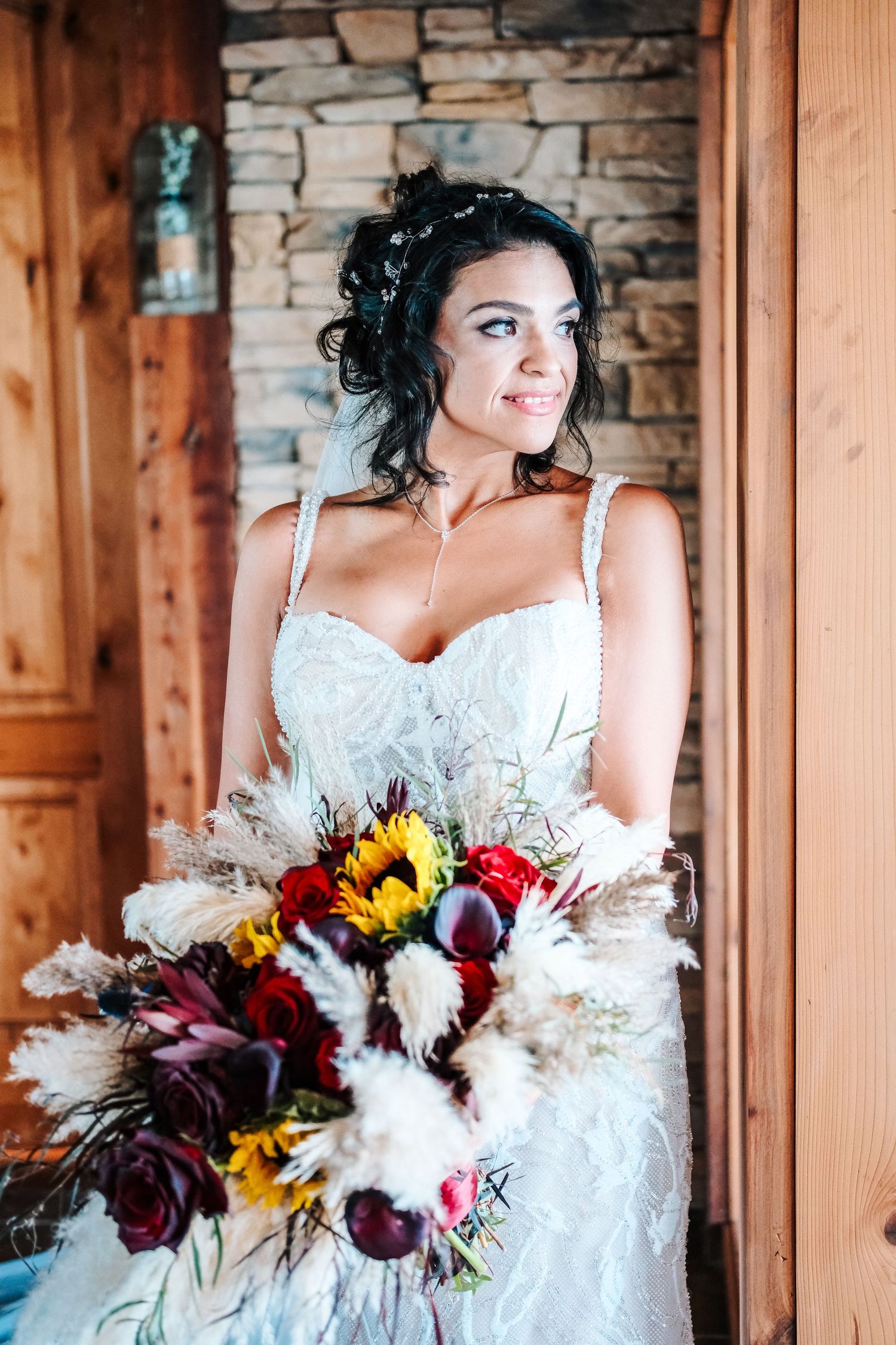 Smiling newlyweds walk hand-in-hand as bride holds boho bouquet and groom wears brown cowboy hat.