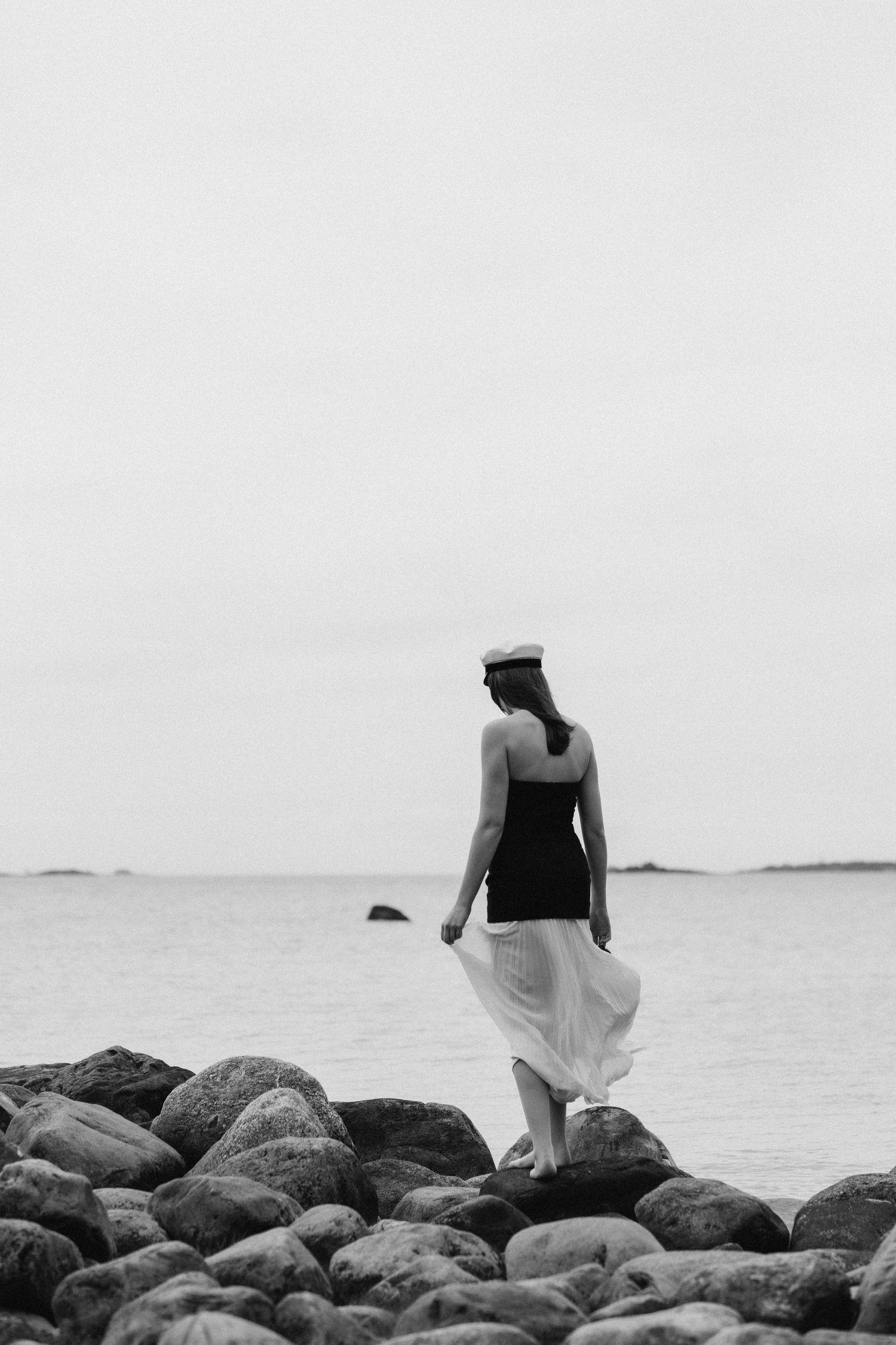 young graduating girl standing on the rocks by the sea