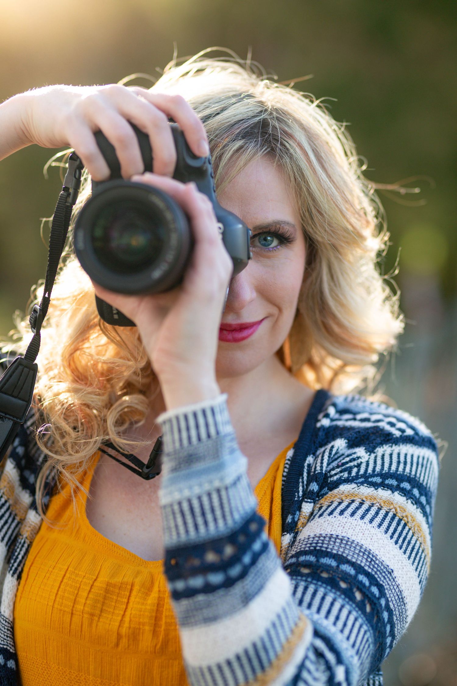 Michele McCoy, wedding photographer in Mountain Home, Arkansas, holding her camera at an outdoor session