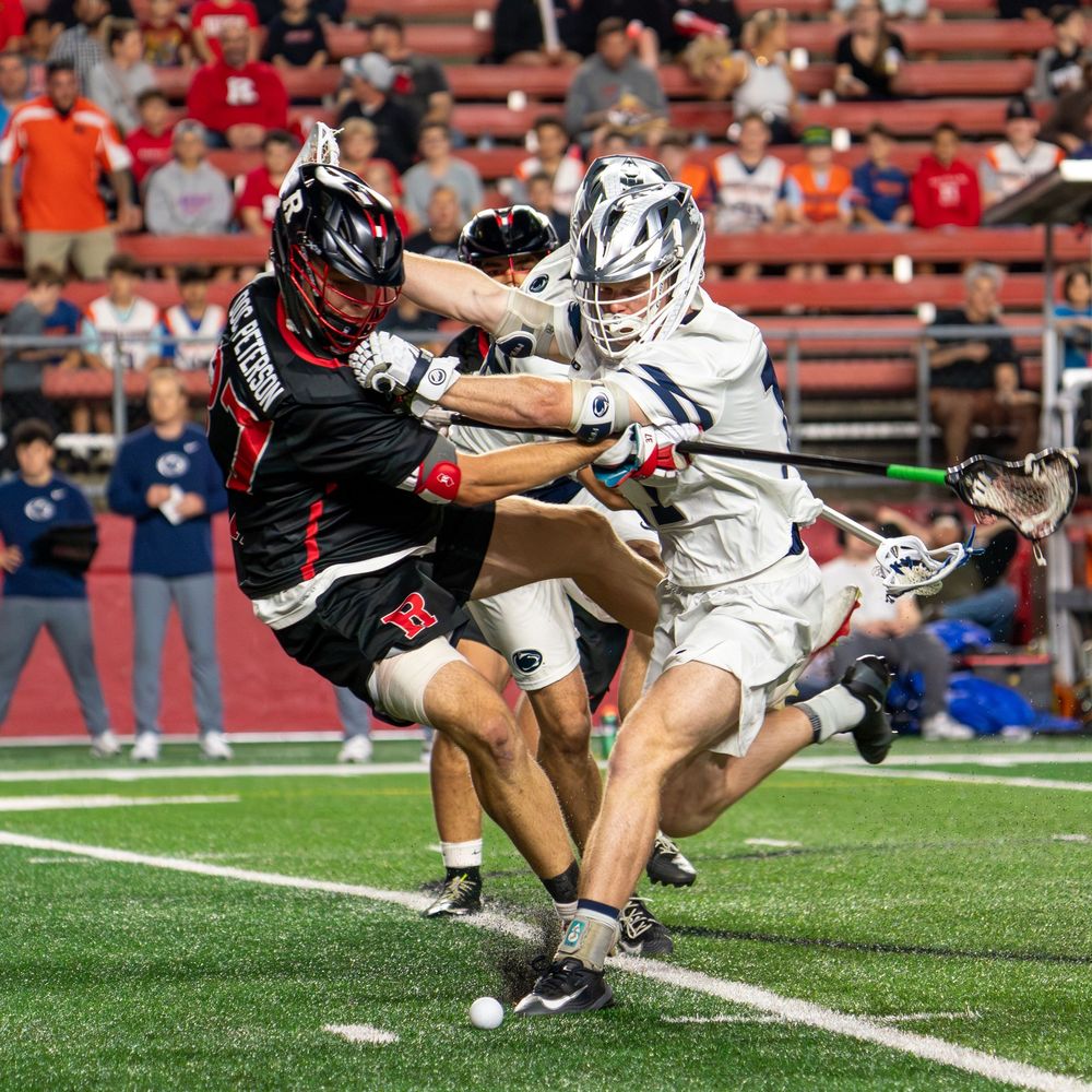 Two lacrosse players battle for a ground ball during an intense college game on a turf field.