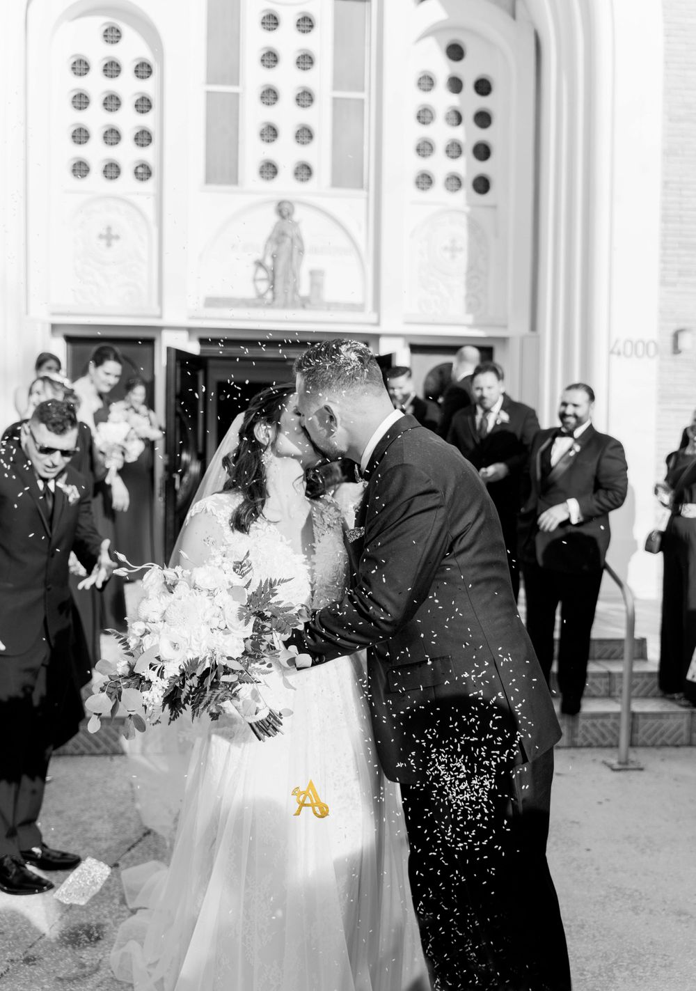 A black and white wedding photo with confetti falling outside a church.