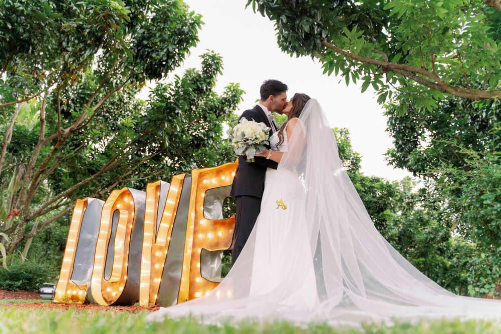 A romantic outdoor wedding scene with large illuminated LOVE letters and floral decorations.