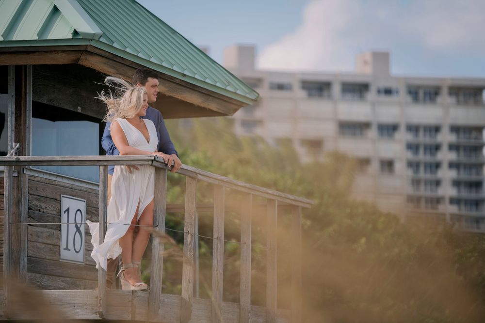 A romantic moment captured on a seaside balcony with a coastal backdrop.