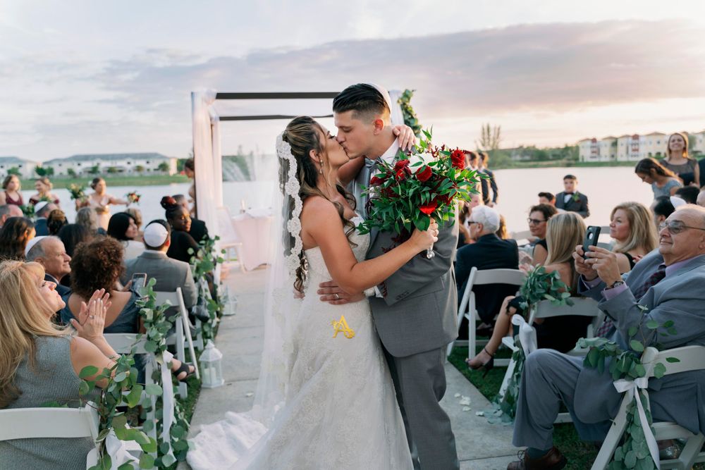 A waterfront wedding ceremony with decorated chairs and floral arrangements.