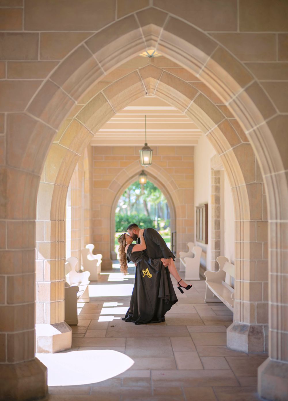 A romantic moment captured under a gothic stone archway with dramatic lighting.