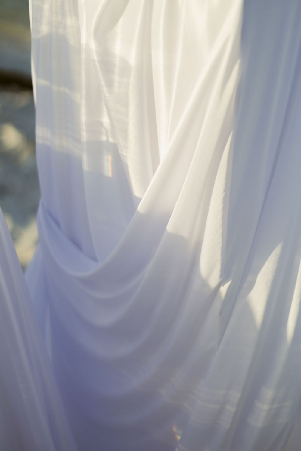 Soft white sheer fabric draped elegantly with light filtering through creating a dreamy effect.