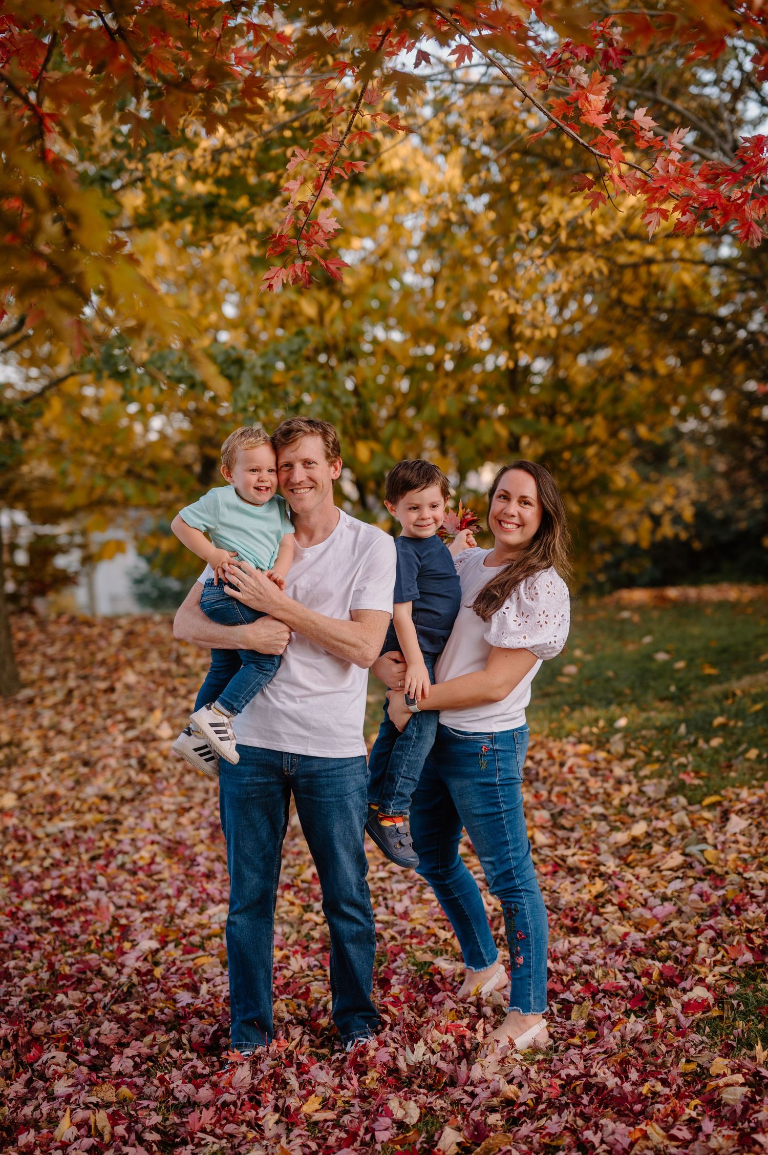 Family of four smiling in fall photos at Cincinnati park