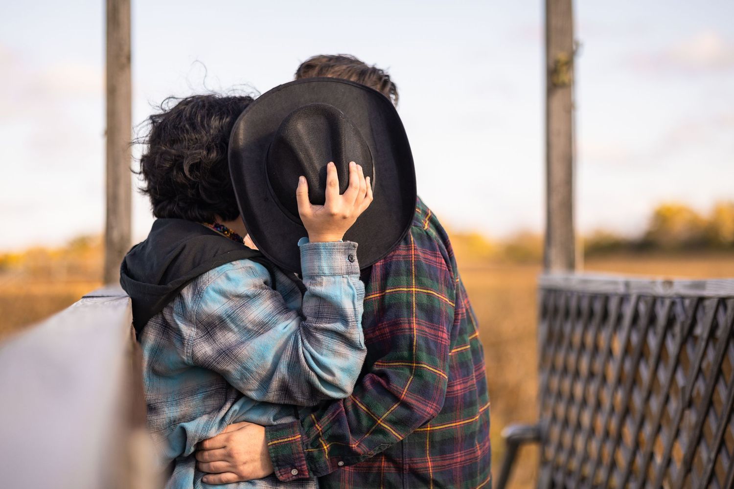 Couple in a colorful autumn park, wearing cowboy hats and plaid shirts with fall foliage backdrop.